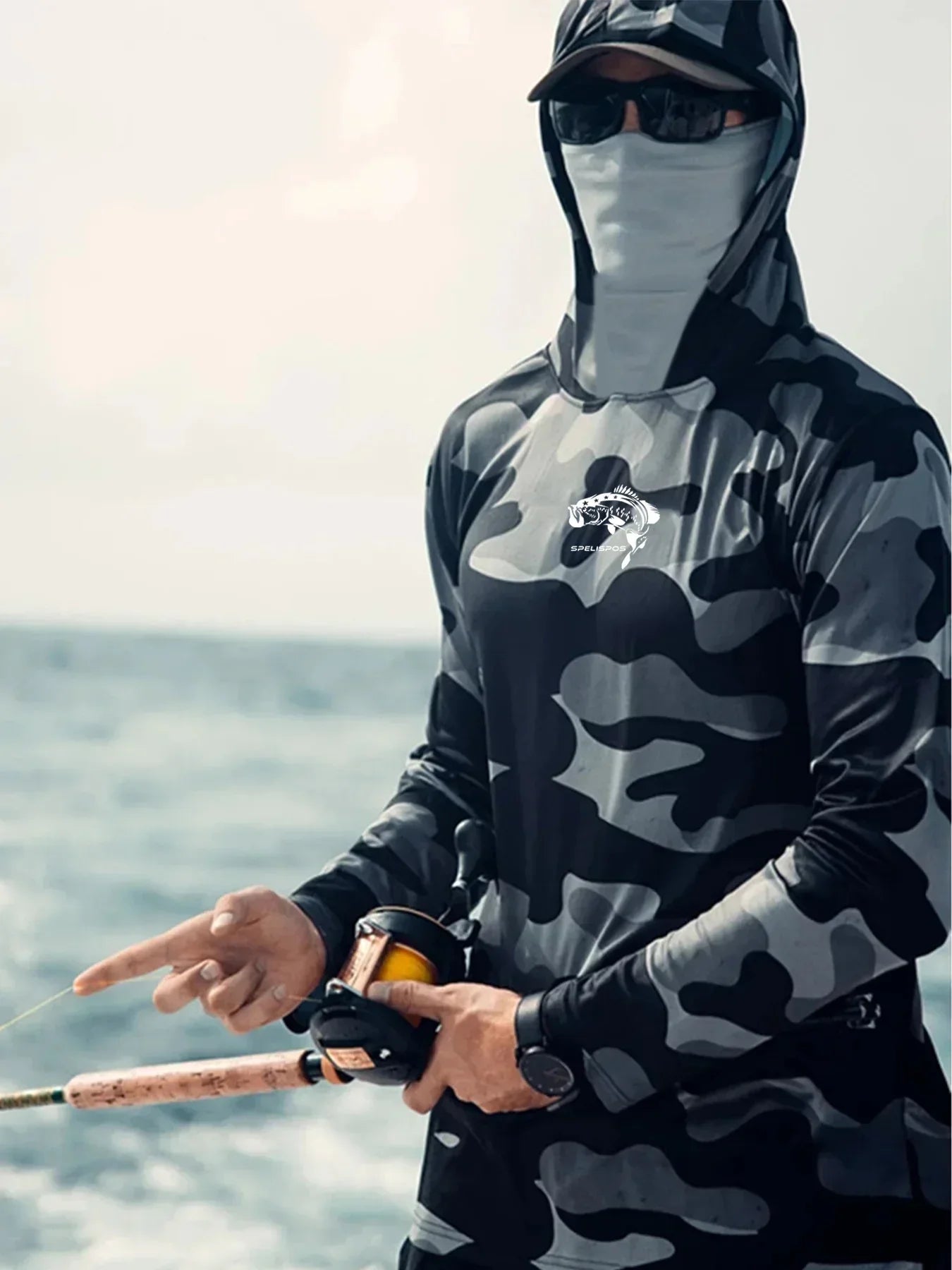 Man in black and gray camouflage hooded long sleeve shirt, face mask, and sunglasses fishing outdoors
