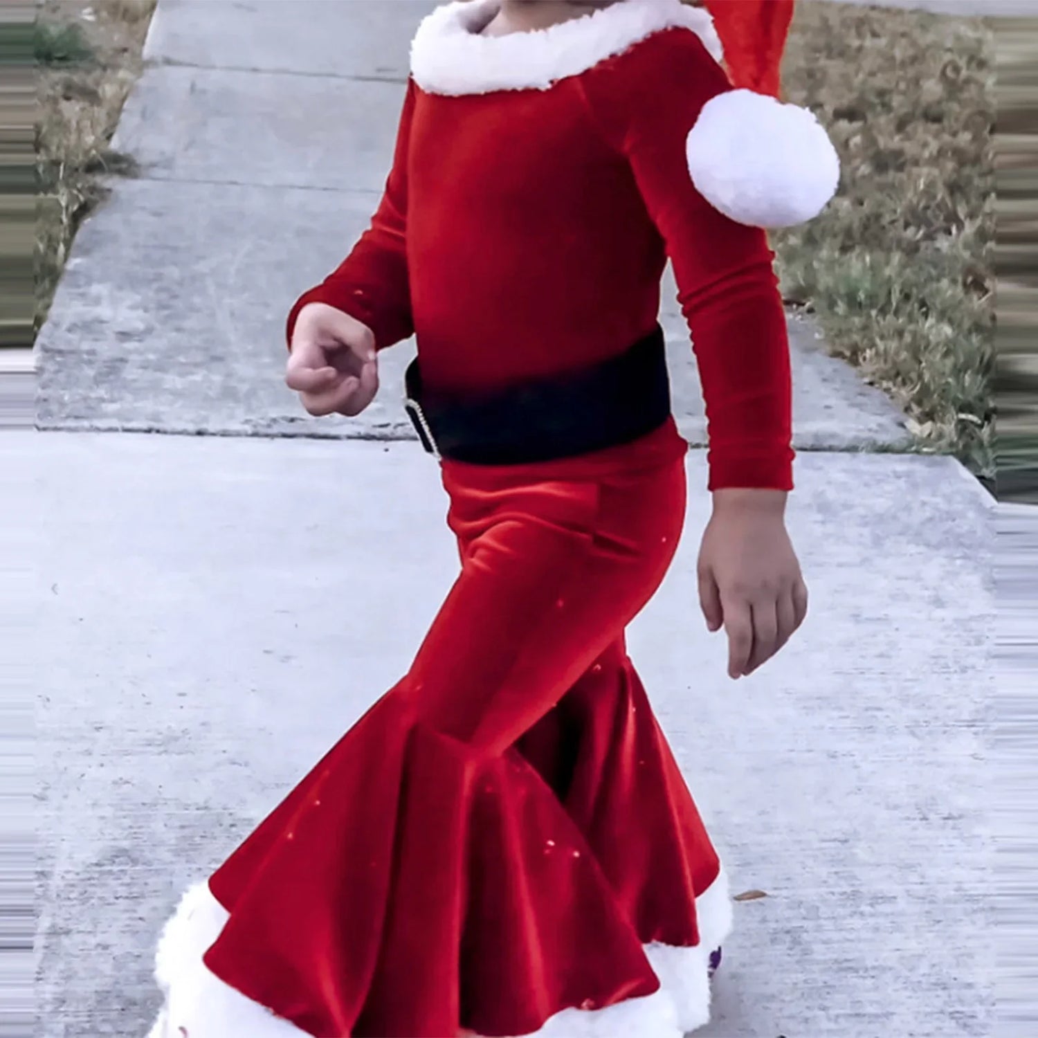 Child wearing red velvet Santa-inspired outfit with white faux fur trim and flared pants