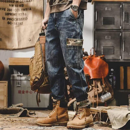 Relaxed fit dark wash cargo jeans with camo pocket, tan boots, and brown canvas backpack