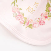 Light pink cotton bib with floral print and soft rounded edge, close up of fabric detail