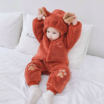Baby in cozy orange fleece hooded onesie with bear ears and paw print details, relaxed fit