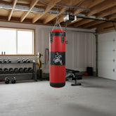 Red leather heavy punching bag with black accents hanging in a home gym setting