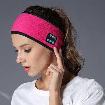 Woman wearing a pink fleece Bluetooth headband with black trim, sporty relaxed fit