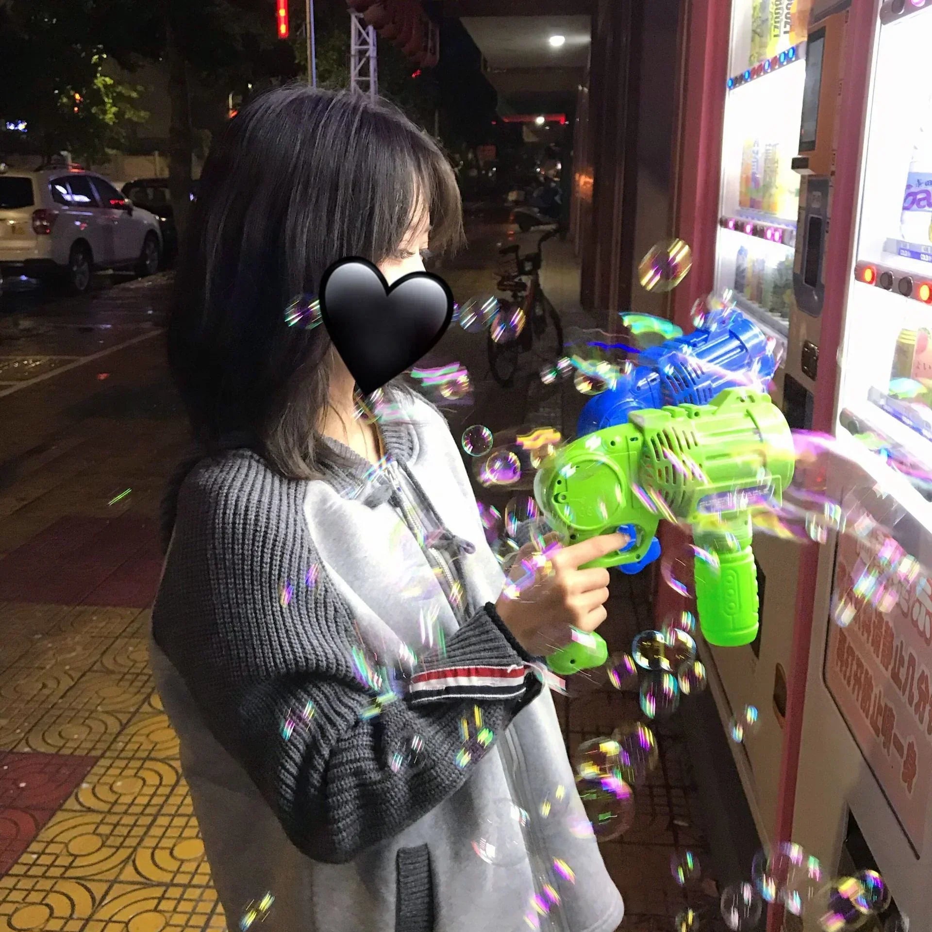 Woman in oversized gray and black knit sweater playing with a bubble gun at night