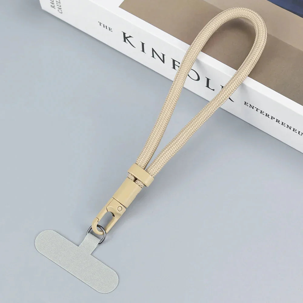 Beige woven lanyard with metal clasp and flat tab, minimalist tech accessory on gray surface