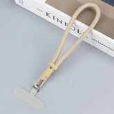 Beige woven lanyard with metal clasp and flat tab, minimalist tech accessory on gray surface