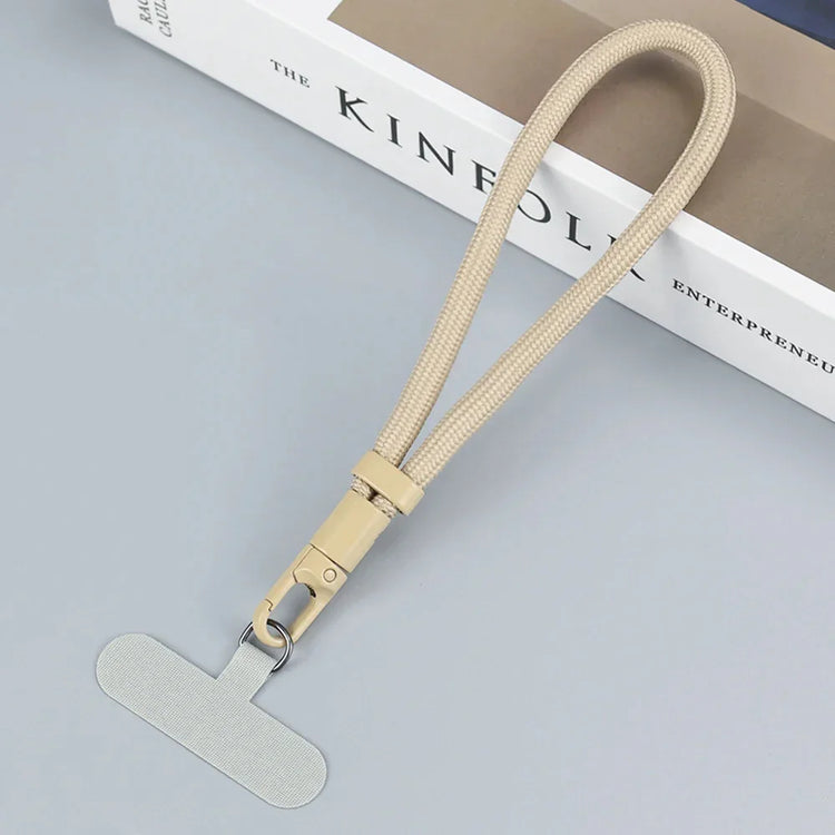 Beige woven lanyard with metal clasp and flat tab, minimalist tech accessory on gray surface