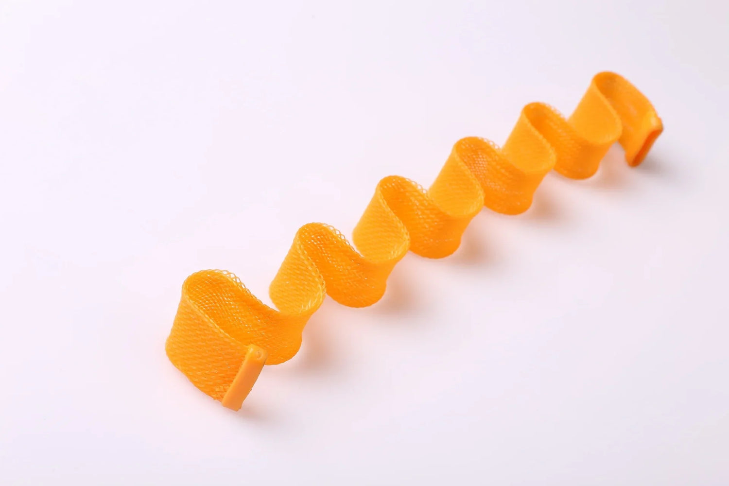 Bright orange mesh ribbon with a wavy, spiral shape, lightweight material on white background