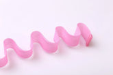 Wavy pink mesh fabric strap with a plastic end, close-up on white background