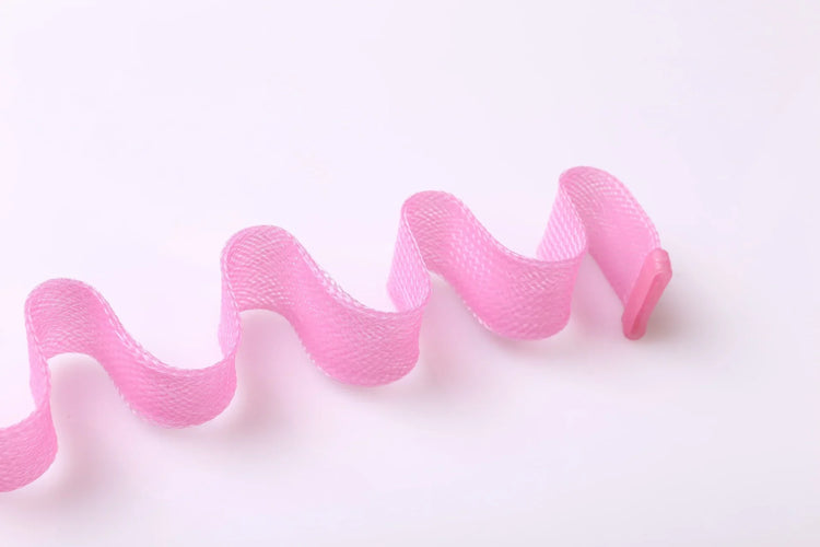 Wavy pink mesh fabric strap with a plastic end, close-up on white background