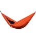 Person in relaxed fit black streetwear lying in bright orange nylon hammock