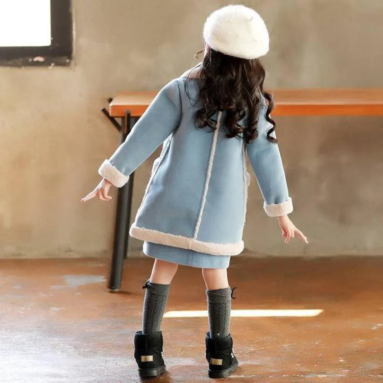 Girl wearing a light blue faux shearling coat with white trim, grey knee socks, and boots