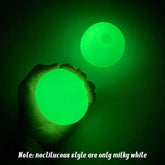 Hand holding round green glow-in-the-dark ball, soft luminous material, dark background