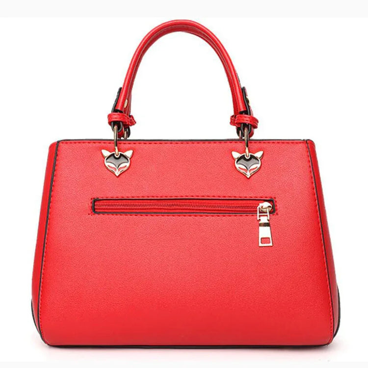 Red faux leather handbag with zipper pocket, gold hardware, and fox head details, structured fit