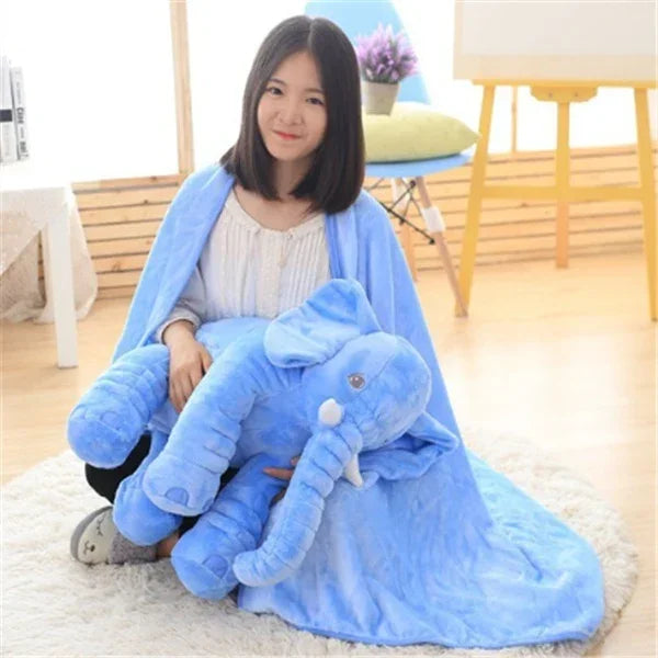 Woman sitting with oversized blue plush elephant toy and wearing soft blue fleece blanket