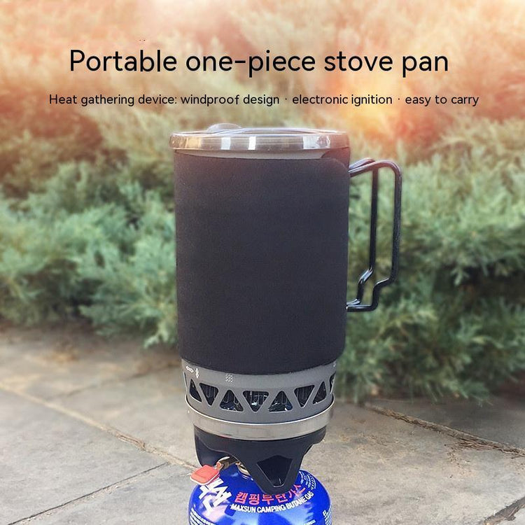 Black insulated portable camping stove pan with metal handle outdoors on stone surface
