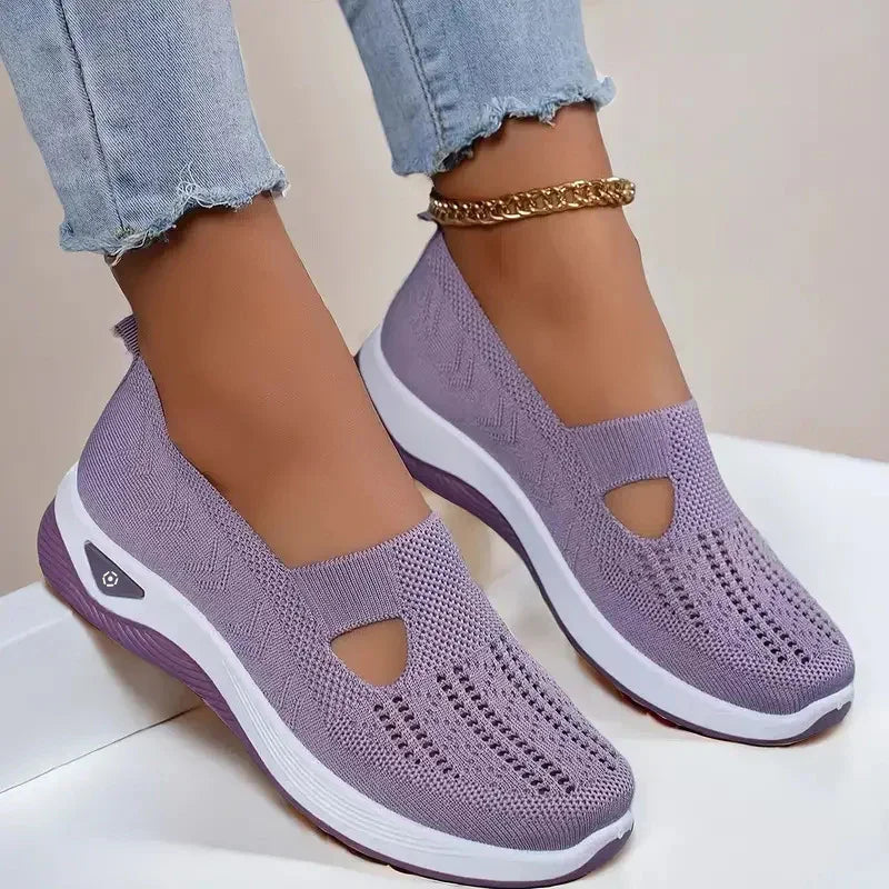 Light purple knit slip-on sneakers with cutout detail and thick white sole, worn with jeans