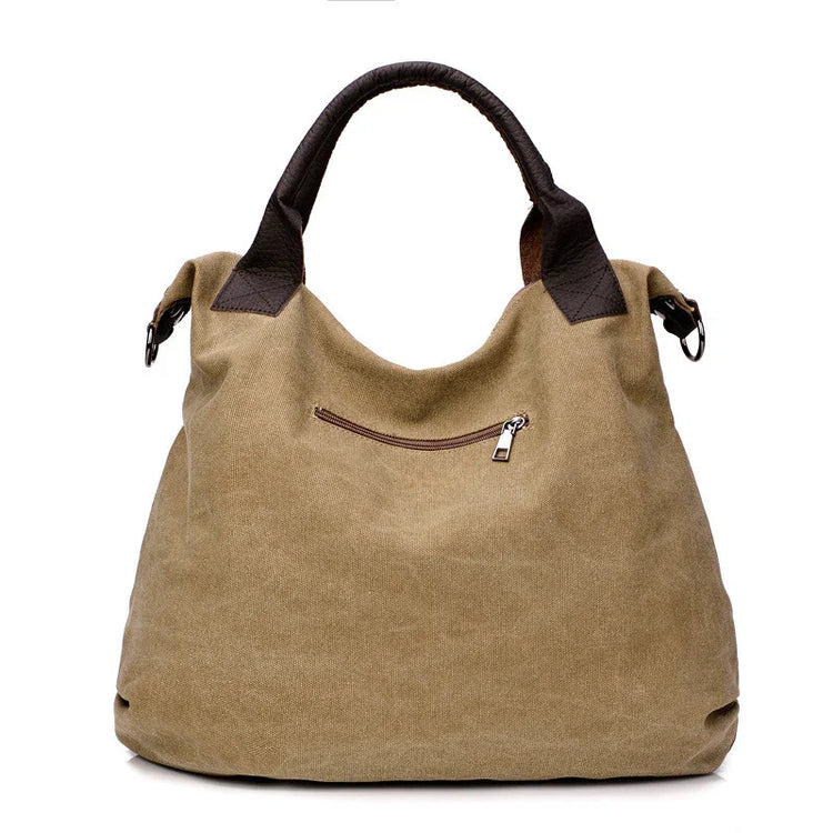 Khaki canvas tote bag with brown faux leather handles and zippered front pocket, relaxed fit