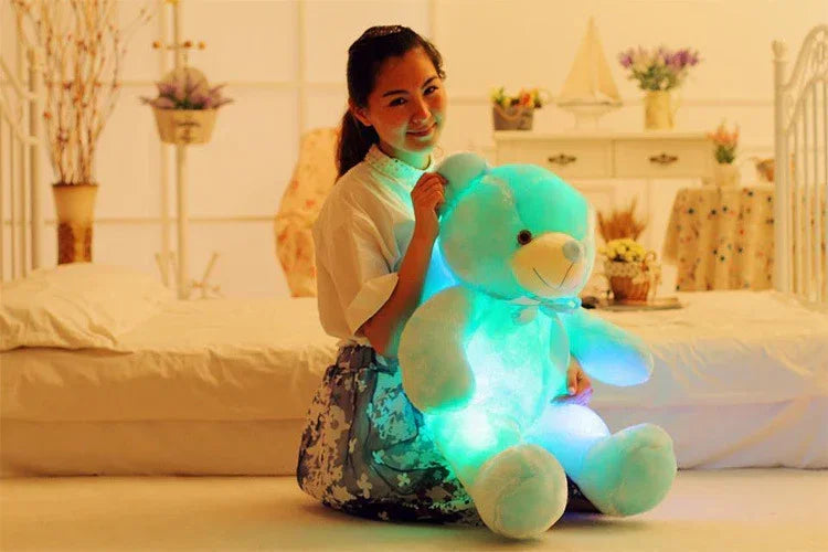 Woman in white blouse and floral skirt with relaxed fit, holding a glowing blue plush bear