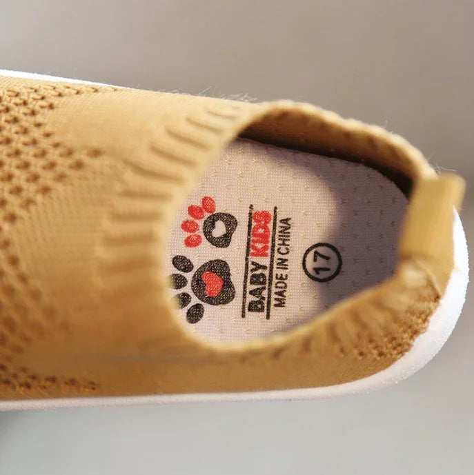 Close-up of tan knit slip-on baby shoe with flexible sole and soft breathable material