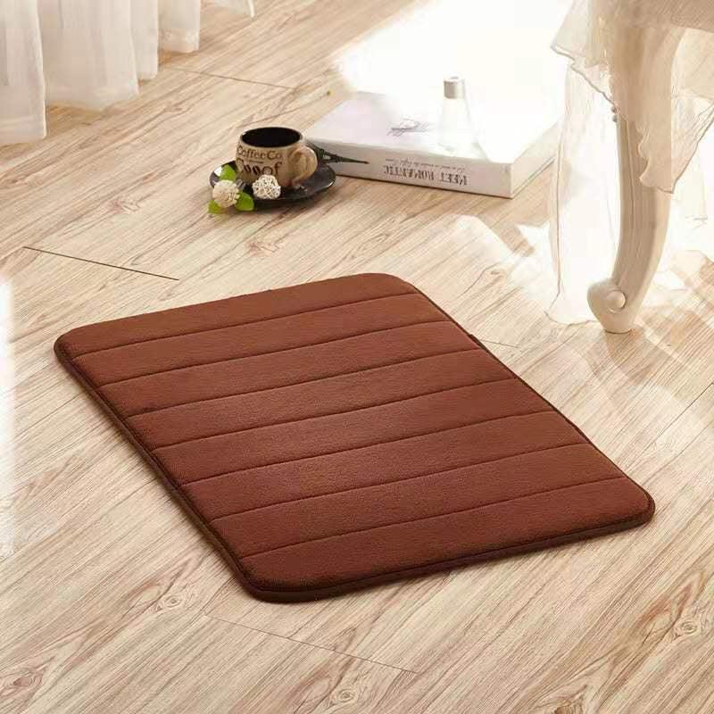 Brown rectangular memory foam floor mat with horizontal stitching on light wood flooring.