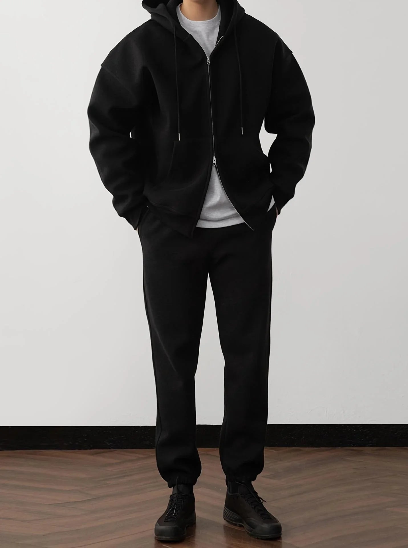 Man wearing black oversized zip hoodie and jogger pants, relaxed streetwear fit