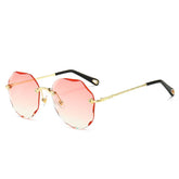 Round rimless sunglasses with wavy pink gradient lenses, gold metal arms, and black tips.