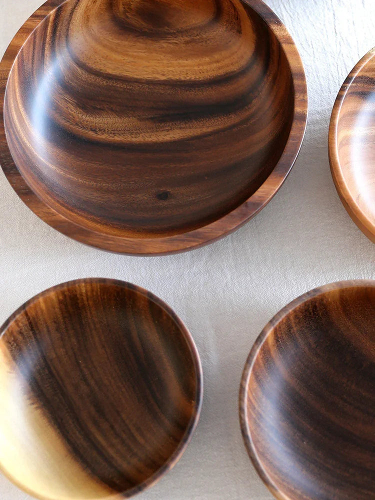 Set of round wooden bowls with rich brown grain and polished finish on neutral fabric surface