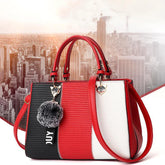 Colorblock handbag with red, black, and white panels, structured fit, faux leather material, fluffy keychain, and top handles