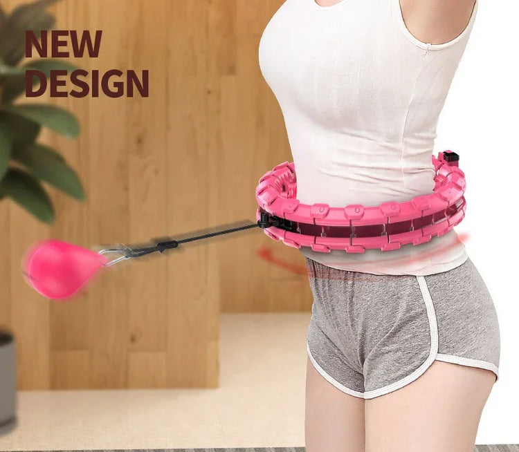 Woman in fitted white top and grey shorts using pink plastic fitness hoop indoors