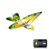 Green and yellow remote control bird toy with black handheld controller, white background