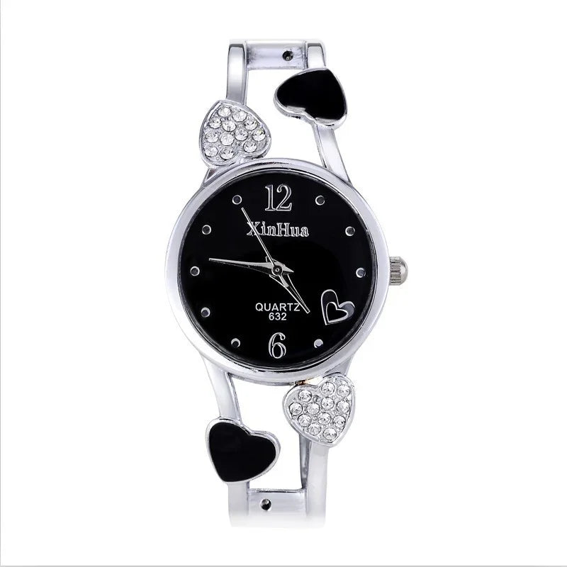 Silver wristwatch with black dial, heart-shaped accents, crystal details, and slim metal band