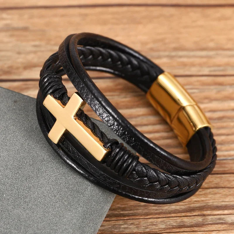 Black braided leather bracelet with gold cross and magnetic clasp on wood surface