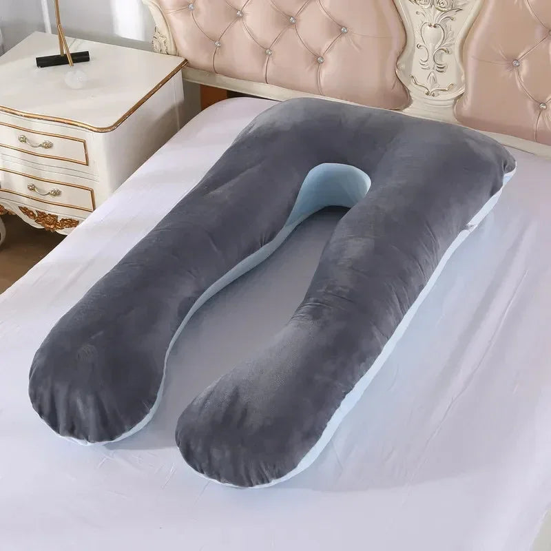 Large U-shaped gray velvet pillow with plush texture on a bed, ergonomic and supportive design