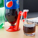 Red plastic drink dispenser stand for soda bottle with glass cup on wooden table