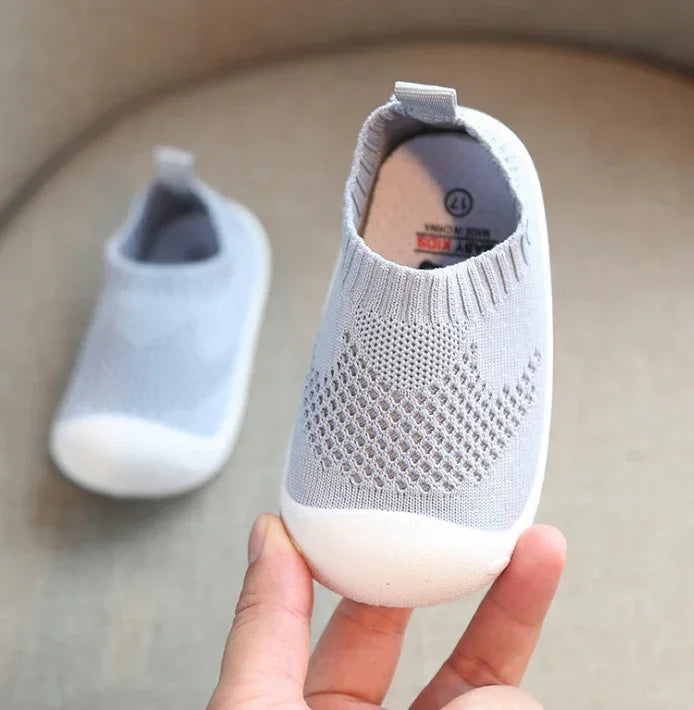 Light grey slip-on baby shoes with knit mesh upper and soft white rubber soles