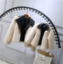 Beige faux fur jackets with black faux leather collars, cropped fit, hanging on rack