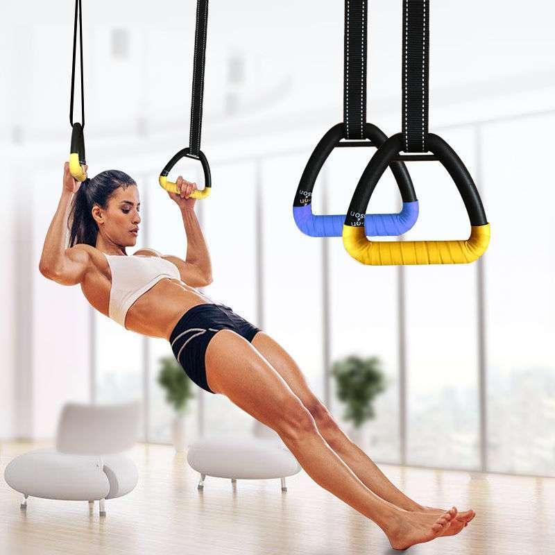 Woman in sporty white crop top and black shorts performing suspension training indoors