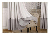 Floor-length light gray and white curtains with thick gray border in a modern living room