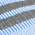 Close-up of light blue ribbed fabric with gray woven stripes, soft textured knit material
