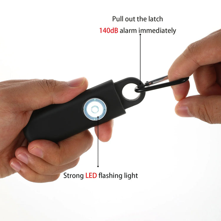 Black personal safety alarm with LED light, compact design, attached to keyring in hand