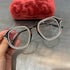 Oversized black square eyeglasses with rhinestone trim and clear lenses, held by hand