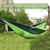 Two-tone blackish green and apple green nylon hammock outdoors, relaxed fit, lightweight material.