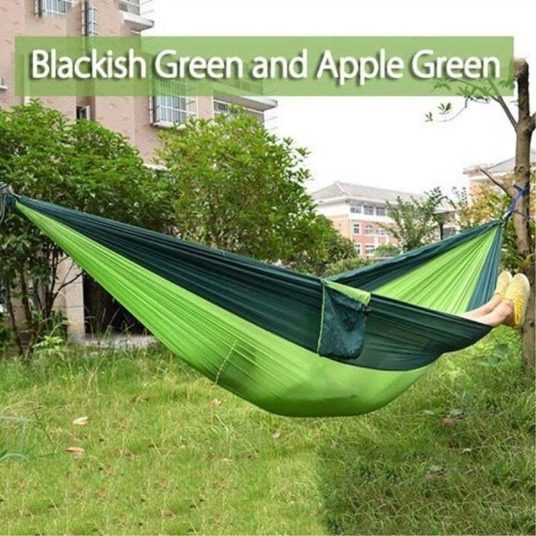 Two-tone blackish green and apple green nylon hammock outdoors, relaxed fit, lightweight material.