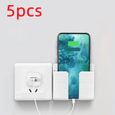 White wall-mounted phone holder next to an electrical outlet with charging smartphone