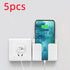 White wall-mounted phone holder next to an electrical outlet with charging smartphone