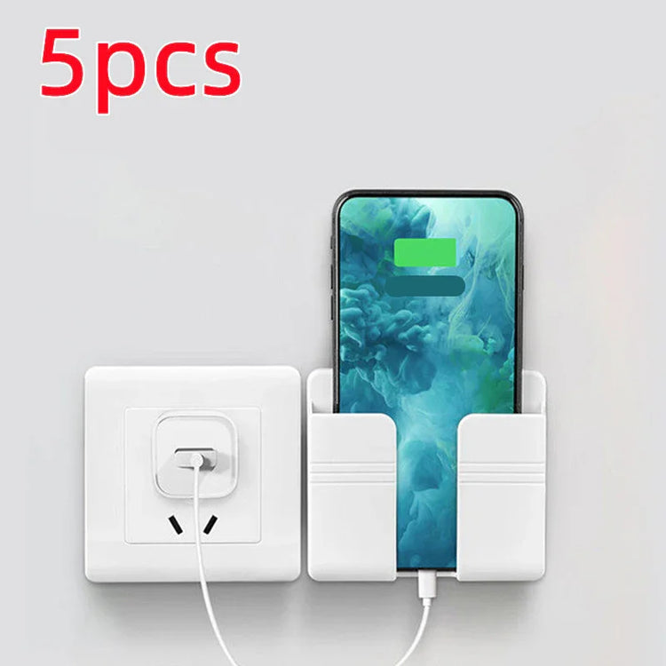 White wall-mounted phone holder next to an electrical outlet with charging smartphone