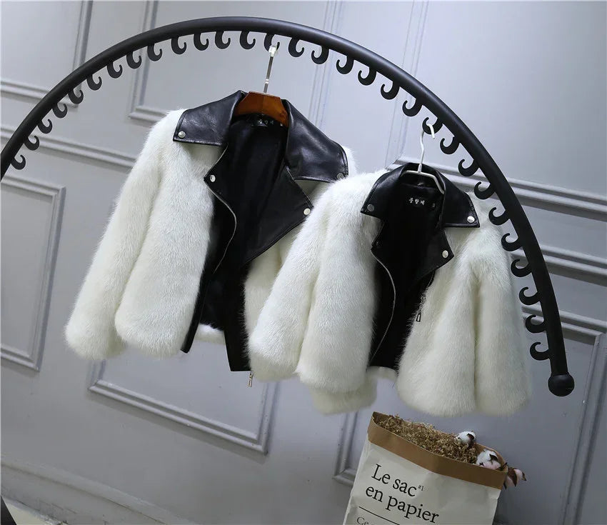 White faux fur jackets with black faux leather collars, cropped fit, hanging on a rack