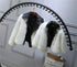 White faux fur jackets with black faux leather collars, cropped fit, hanging on a rack