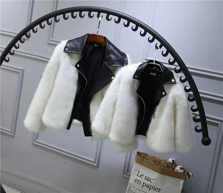 White faux fur jackets with black faux leather collars, cropped fit, hanging on a rack